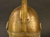 an antique helmet on a stand against a black background
