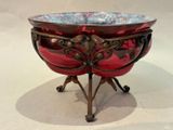 a red bowl on a stand on a white surface