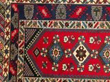 an image of a red, blue, and black rug with a diamond design