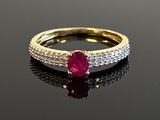 a close up of a ruby and diamond ring on a black surface