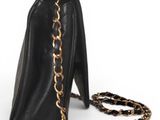 black leather handbag with gold chain strap on a white background