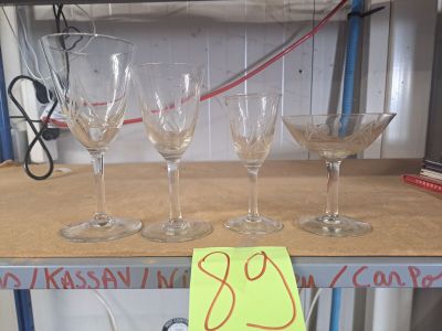 Plusieurs verres à vin vides sont posés sur une étagère, accompagnés d'une étiquette de prix.