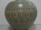 a green vase sitting on a table with a white wall in the background