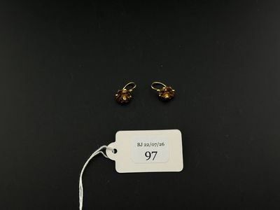 a pair of gold earrings on a black background with a price tag