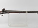 un pistolet au canon en bois posé sur un socle transparent