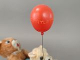 two stuffed animals in a toy car with a red balloon