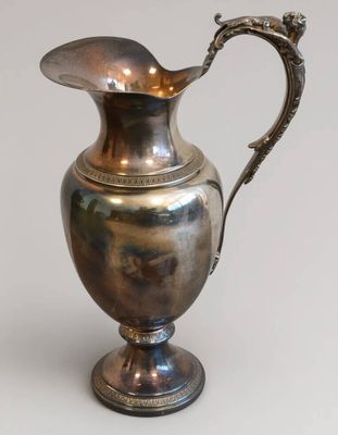 un pichet ancien en argent orné d'une poignée en forme de dragon sur fond blanc