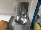 un lavabo dans un coin d'une pièce, avec une chaise