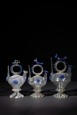 four glass vases with blue and white designs on them on a black surface