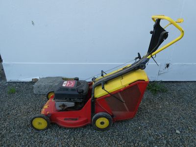 une tondeuse à gazon rouge et jaune posée par terre