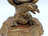 a clock that is sitting on a stand with a bird on it