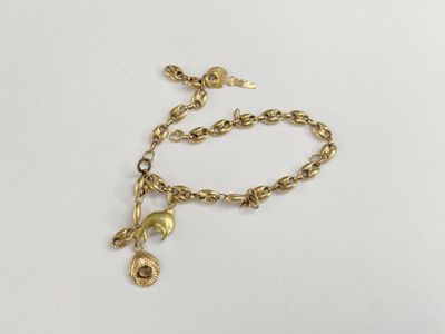 a close up of a gold chain bracelet with a bell charm