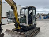 a yellow and black excavator sitting in a parking lot