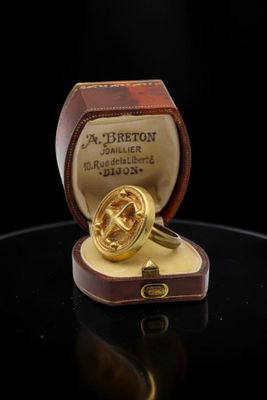 an image of a gold ring in a box on a black surface