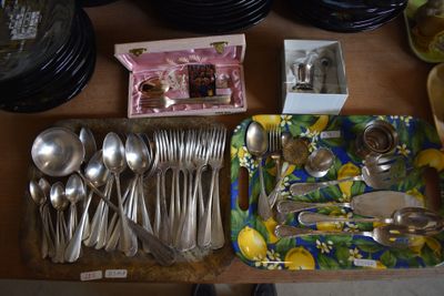 a lot of silverware on a table with plates and spoons