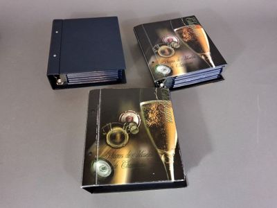 trois livres posés sur une table, avec un verre de vin devant eux