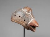 a wooden mask on a stand with a gray background