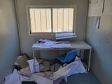 a room with a desk, chair, and a lot of papers on the floor