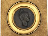 an old coin with a man ' s head on it in a gold frame