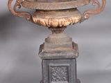 a very old looking vase on a pedestal on a gray background