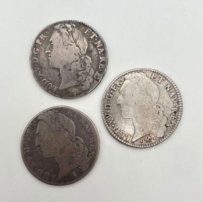 trois types différents de pièces d'argent sur une surface blanche