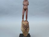 statue d'un homme debout sur un rocher, les mains dans les poches