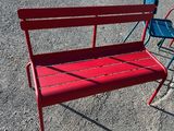 a red bench and a blue chair in a parking lot