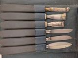 several knives are lined up in a leather case on a table