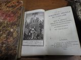 un vieux livre posé sur une table en bois, à côté d'une assiette en argent