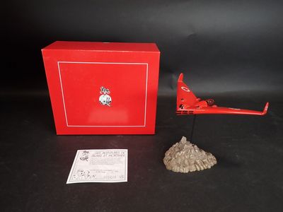 un vieil avion jouet rouge posé sur une table, à côté d'une boîte rouge