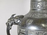 a large metal vase with a dragon handle on it