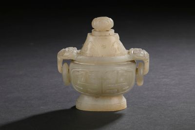 un vase blanc muni d'un couvercle, posé sur une table