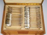a lot of silverware in a wooden box on a table