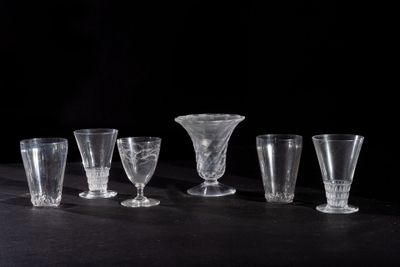 six clear glass goblets are lined up on a black table