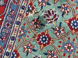 close up of a blue and red rug on a wooden floor