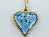 a blue heart shaped pendant with flowers on it