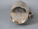an old silver cup sitting on top of a table next to a metal object