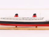une maquette de bateau dans une vitrine, posée sur un socle en bois