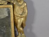 a gold statue of a boy and a mirror on a table