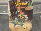 un bocal contenant des objets du jeu de cartes à collectionner Pokémon posé sur une table