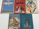 several children ' s books are lined up on a white surface