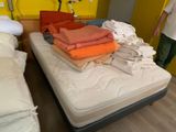 un homme debout à côté d'un lit recouvert de nombreuses couvertures