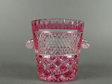 un vase en verre rose muni d'une anse, posé sur une table