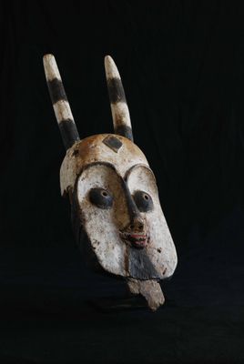 un gros plan d'un masque en bois muni de cornes sur fond noir