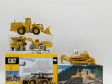 two yellow construction vehicles sitting on top of each other on a white surface