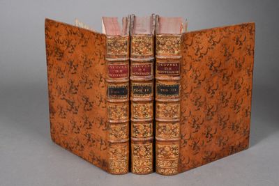 two old books sitting on top of each other on top of a table