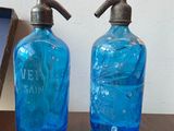 two blue glass bottles on a table with a metal faucet
