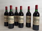 six bottles of wine are lined up on a table