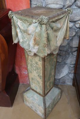 a stone pedestal with a cloth covering it in front of a stone wall