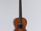 an old guitar hanging on a wall with a white background